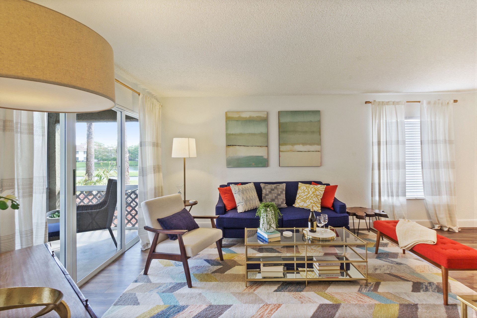 Living room with patterned area rug and colorful couch, chair, and ottoman with coffee table
